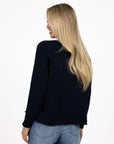Model in studio wearing Divine Jumper in Navy with Ryder Jean, close-up back view 