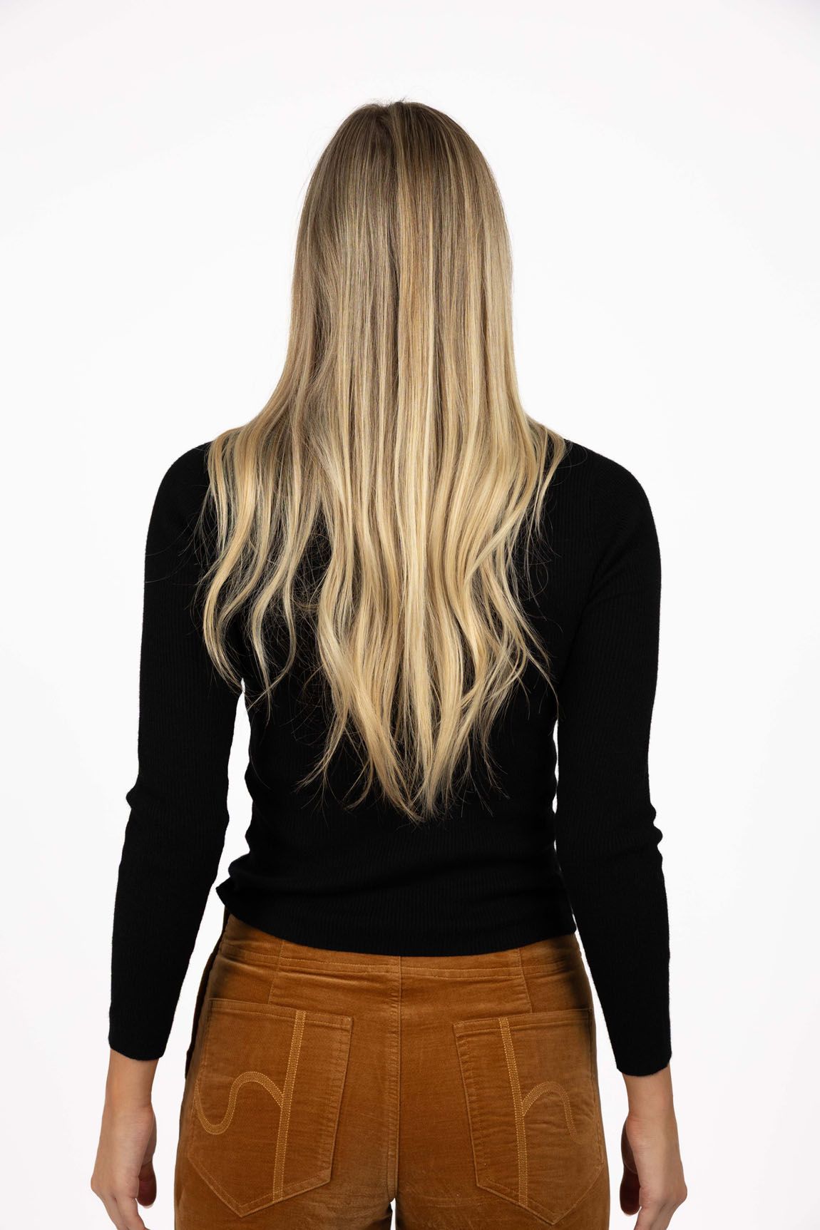 Model in studio wearing Tempo Top in Black with Stitched Luxe Pant in Camel, close-up back view  