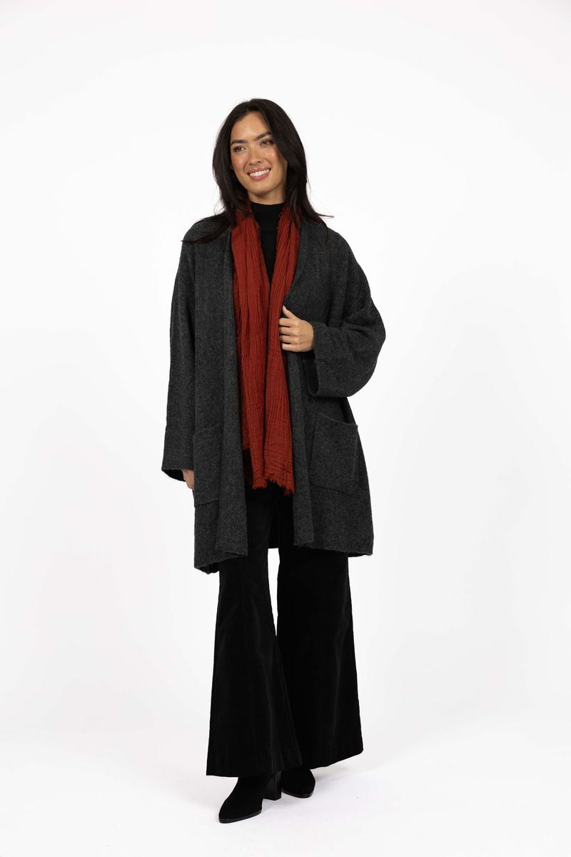 Model in studio wearing Rosha Cardi in Charcoal over Va Va Velour Pants in black with Luxe Wool Scarf in Rust, full-length front view 