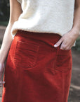 Model in lifestyle setting wearing Va Va Velour skirt in Rust with Monet Vest in Cream, close-up front view showing patch pockets  