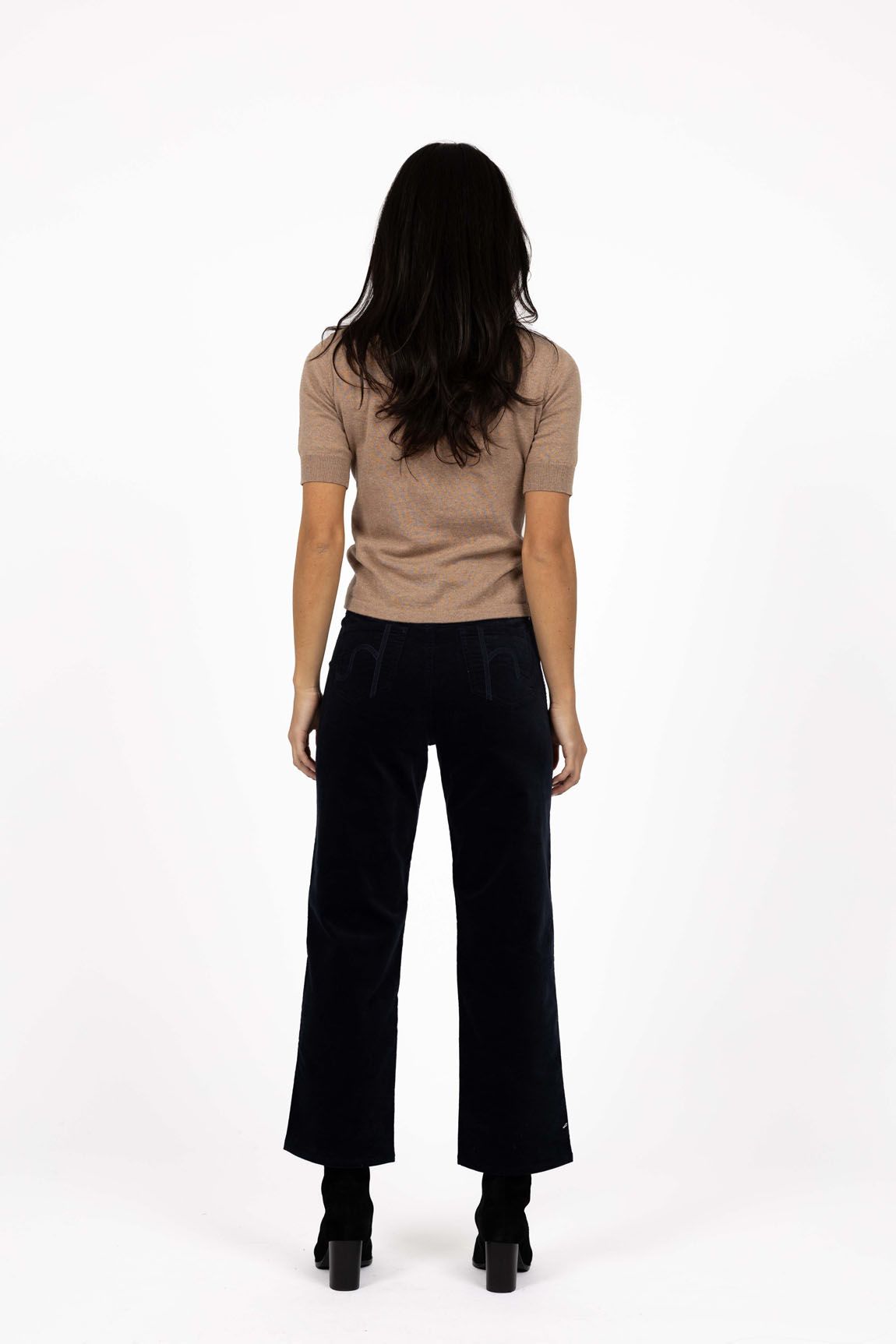 Model in studio wearing Va Va Velour Pant in Navy with Vera Top in Hazelnut and black boots, full-length back view 