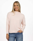 Model in studio wearing Divine Jumper in Pink with Ryder Jean, close-up front view with hand in jean pocket 