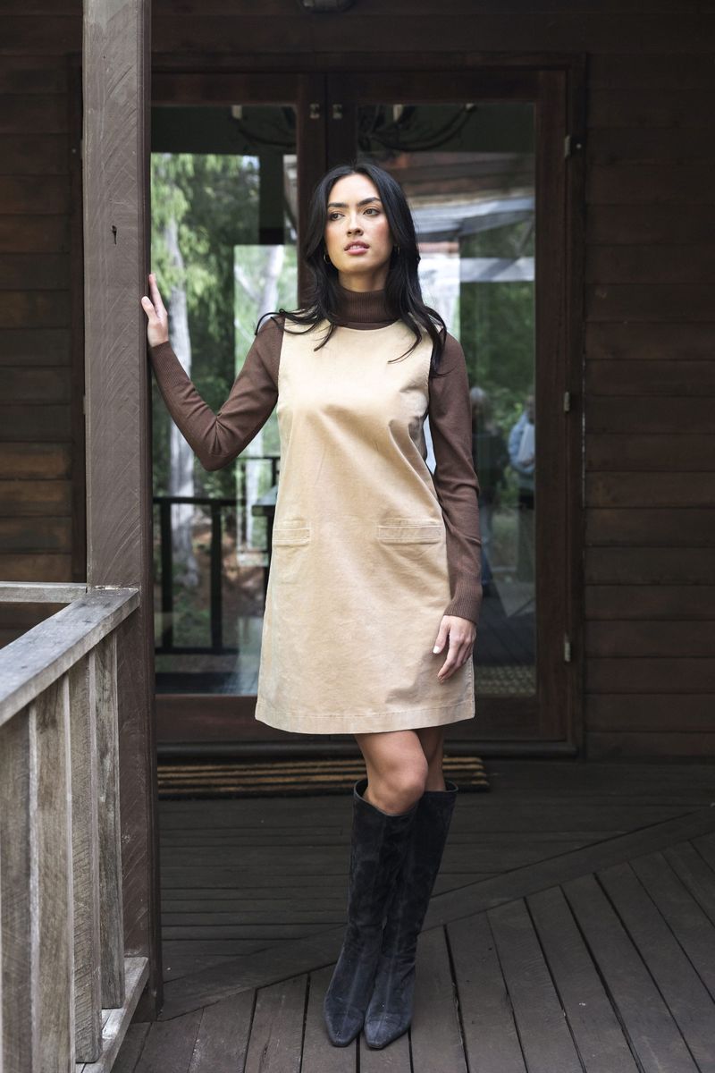 Model in lifestyle setting wearing Nova Cord Dress in Wheat over the Alana Skivvy in Chocolate with black boots, full-length front view  