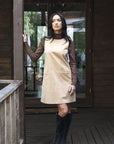 Model in lifestyle setting wearing Nova Cord Dress in Wheat over the Alana Skivvy in Chocolate with black boots, full-length front view  