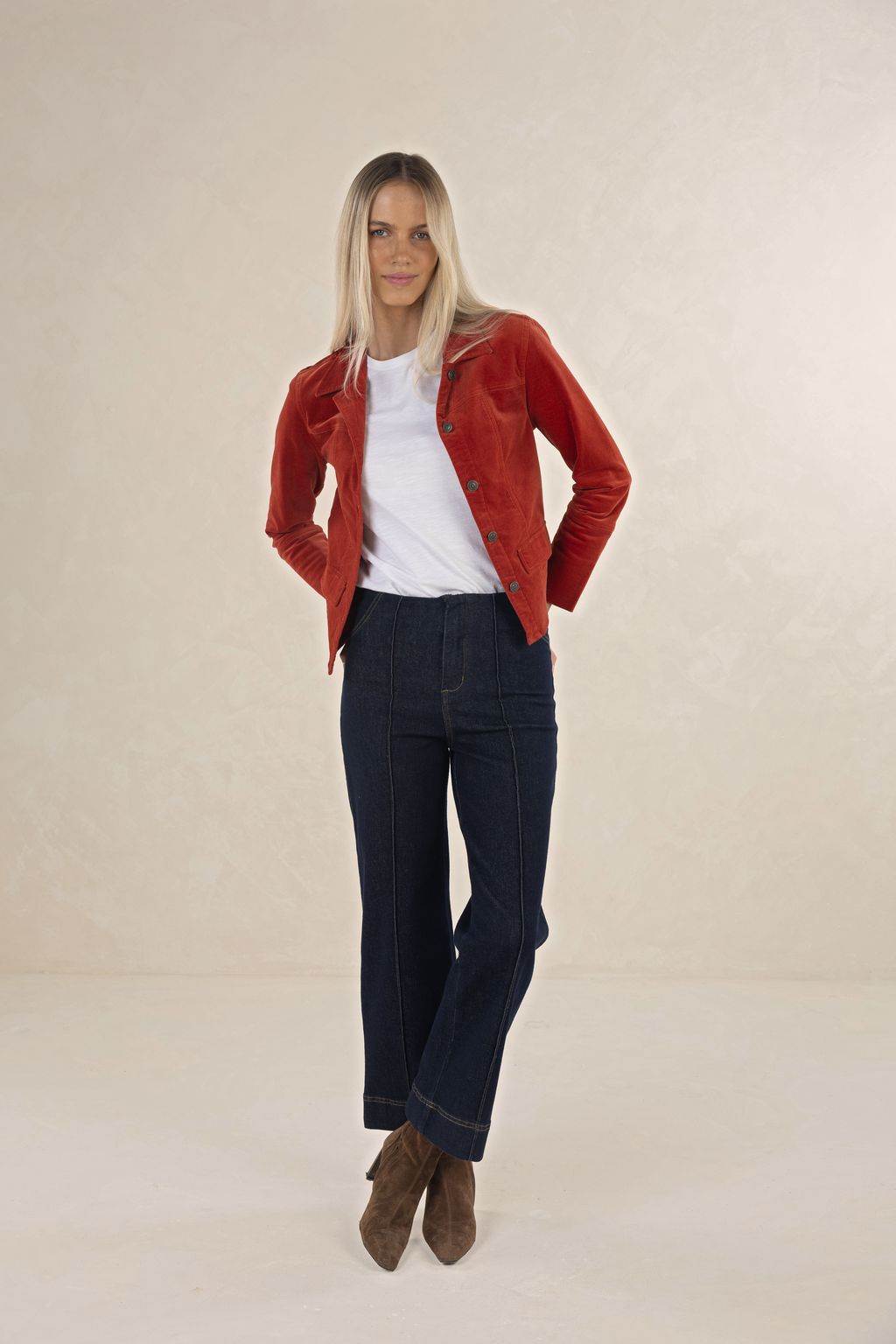 Model in studio wearing Gabi Jacket in Rust over white Bene Tee and Escapade Jean with brown boots, full-length front view 