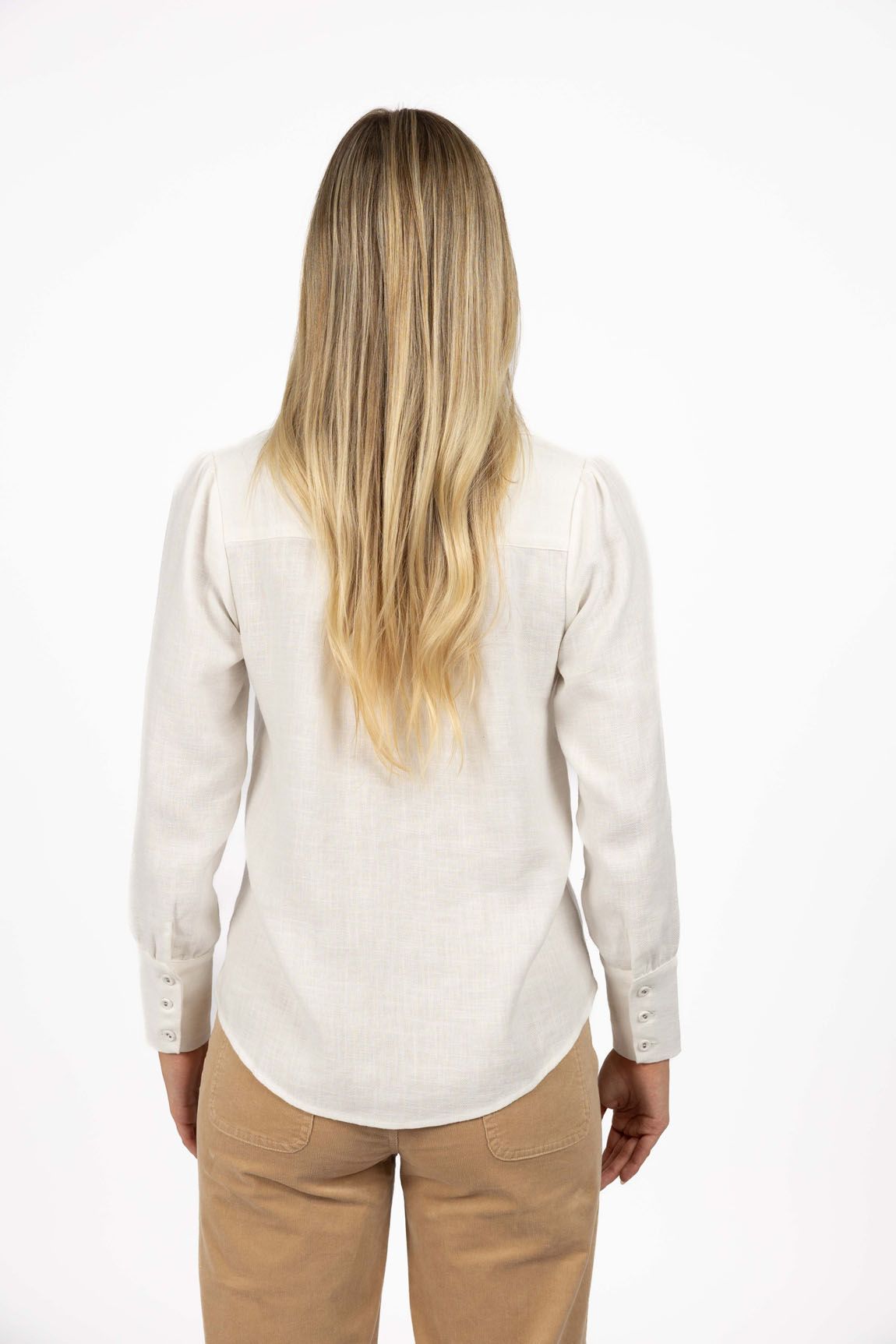 Model in studio wearing Pixie Shirt in White with Fleetwood Cord Pant in Wheat, close-up back view showing round hem 
