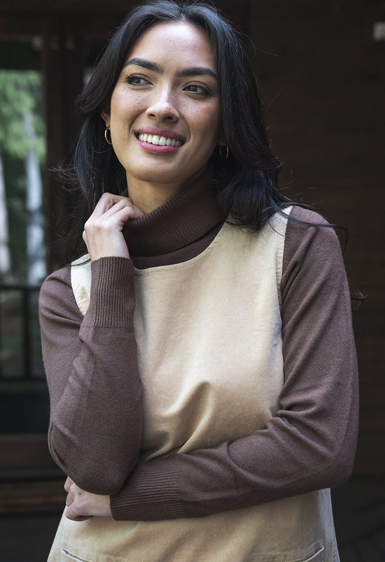 Model in lifestyle setting wearing Alana Skivvy in Chocolate with Nova Cord Dress in Wheat, close-up front view showing ribbed collar and cuff 