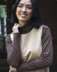 Model in lifestyle setting wearing Alana Skivvy in Chocolate with Nova Cord Dress in Wheat, close-up front view showing ribbed collar and cuff 