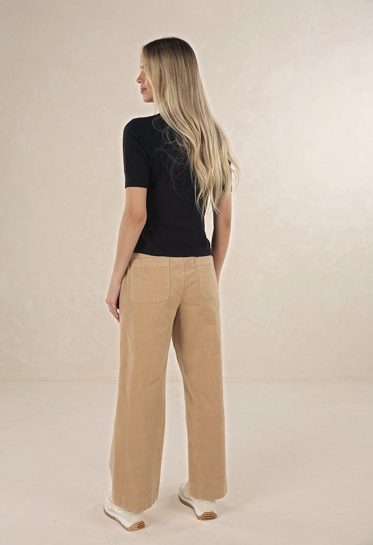 Model in studio wearing Suki Cord Pant in Wheat and Vera Top in Black with cream sneakers, full-length back view 
