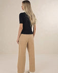Model in studio wearing Suki Cord Pant in Wheat and Vera Top in Black with cream sneakers, full-length back view 